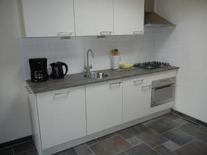 una cocina con armarios blancos y fregadero en Mooi zo 2, en De Koog
