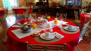 a table with a red table cloth with food on it at La Ferme de Jeanne in Saint-Girons