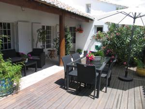 a wooden deck with a table and chairs and an umbrella at Mas de charme Les Pellegrins in Saintes-Maries-de-la-Mer