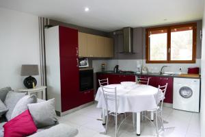 une cuisine avec une table blanche et des placards rouges dans l'établissement la ferme du parroi, à Annecy