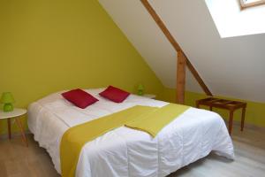- une chambre dotée d'un lit blanc avec des oreillers rouges et jaunes dans l'établissement la ferme du parroi, à Annecy