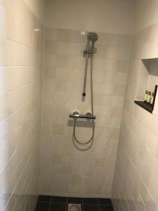 a shower with a hose in a tiled bathroom at B&B 'het Gripshuis' in Vught