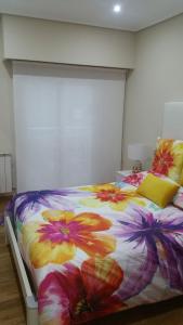 a bedroom with a bed with a floral comforter at Apartamento Centro Porriño in Porriño