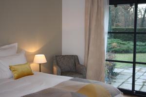 a bedroom with a bed and a chair and a window at Les Enclos Bed and Breakfast à 4 mn de Chantilly in Lamorlaye
