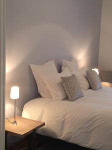 um quarto com uma cama branca com almofadas e uma mesa em Les Enclos Bed and Breakfast à 4 mn de Chantilly em Lamorlaye
