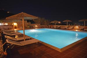 a large swimming pool with chairs and an umbrella at Paradisia Villas in Naxos Chora