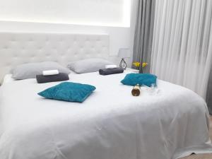 a white bed with two blue pillows on it at Abbazia Apartments Free Parking Near Center and Vrbas River in Banja Luka +30 photos