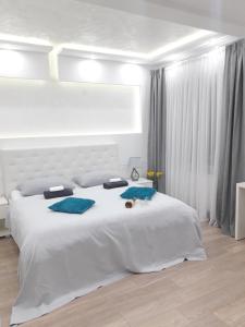 a white bedroom with a large white bed with blue pillows at Abbazia Apartments Free Parking Near Center and Vrbas River in Banja Luka