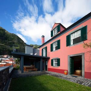 a red house with a balcony and a yard at Casa do João da Eira in Seixal