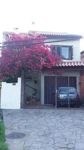 Una casa con una puerta con flores rosas. en Pousada da Tetê, en Porto Alegre