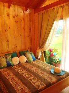 a bedroom with a large bed with a window at Arriendo de Cabañas con Piscina y Entorno Natural, Villarrica in Villarrica