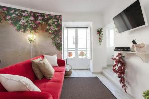 リスボンにあるThe Garden - Charming 1 Bedroom Apartment in Graçaの赤いソファ付きのリビングルーム、壁に花を飾るリビングルーム