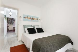 リスボンにあるThe Garden - Charming 1 Bedroom Apartment in Graçaの白いベッドルーム(黒い枕の大型ベッド付)