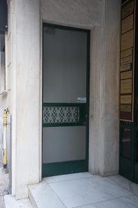 une porte verte sur le côté du bâtiment dans l'établissement Dimokritou 4 Apartment, à Athènes