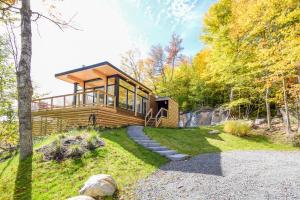 a house in the woods with a pathway leading to it at Modern Chalet with Mountain and Lake view by Reserver.ca in Sainte-Adèle
