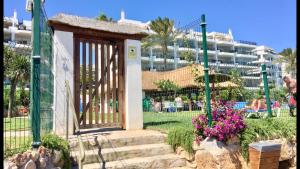a gate in a park with a resort in the background at MI CAPRICHO 9B BEACHFRONT- Apartment with sea view - Costa del Sol in Mijas Costa
