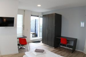 a living room with a black cabinet and two red chairs at looks-inn in Viernheim