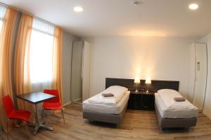 a bedroom with two beds and a table and chairs at looks-inn in Viernheim
