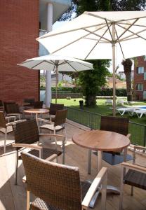patio ze stołami, krzesłami i parasolami w obiekcie SG Costa Barcelona Apartments w mieście Castelldefels