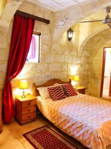 a bedroom with a large bed with red curtains at Molendini in Għarb