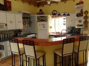 a kitchen with a counter with four chairs at a bar at Pointe Dubique Bed and Breakfast in Calibishie