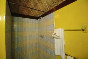 uma casa de banho amarela com um chuveiro e uma toalha em Cohune Palms River Cabanas em Bullet Tree Falls