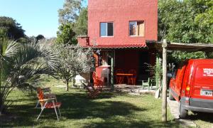 a red house with a red truck parked in front of it at Casa de Amelia (Punta Rubia) in La Pedrera