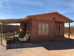 a small wooden cabin with two chairs in front of it at Cabaña Laynaturi in San Pedro de Atacama