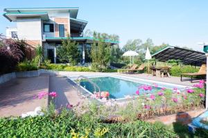 a swimming pool in front of a house with flowers at Khao Kho Overview Resort in Khao Kho