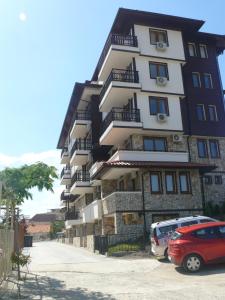 a tall building with cars parked in front of it at Complex Kentavar - Free Fast WiFi in Sveti Vlas