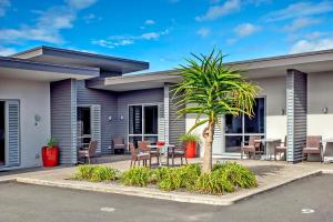 a house with a palm tree in front of it at 37 The Landing Motel in Whakatane