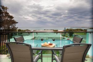 balcón con mesa y 2 copas de vino en The Dolphin Apartments en Apollo Bay