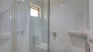 a white bathroom with a shower and a toilet at Moama Central Motel in Echuca