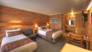 a hotel room with two beds and a desk at Moama Central Motel in Echuca