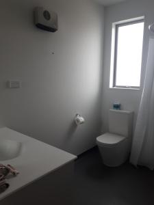 a white bathroom with a toilet and a window at Northpark Motel in Timaru
