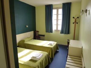 a hotel room with two beds and a window at Hôtel Croix des Nordistes in Lourdes