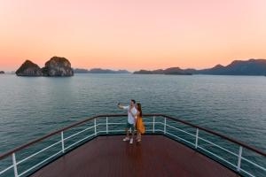 a man and a woman standing on the deck of a boat at Emeraude Classic Cruises in Ha Long