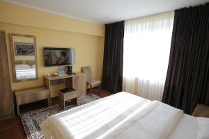 a bedroom with a bed and a desk and a mirror at Altai Business Hotel in Almaty +109 photos