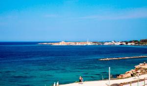 a group of people walking on a beach near the water at Amphora Hotel & Suites in Paphos