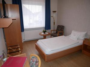 um quarto com uma cama, uma cadeira e uma janela em Haus Nethegau em Bad Driburg