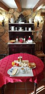a table with a red table cloth with food on it at Hotel Rural La Casa de los Tres Cielos in Campo de Criptana