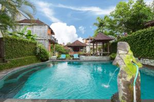 a pool with a statue in front of a house at Sayong House in Ubud