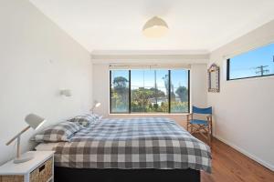 a bedroom with a bed and a large window at 74 Ocean Parade in Dalmeny
