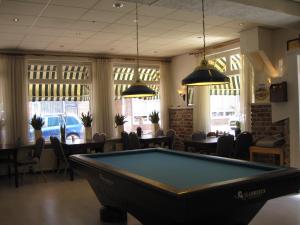 a pool table in a room with tables and chairs at Hotel Valkenhof in Zoutelande