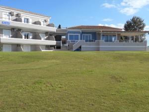 una casa grande con césped delante en Blue Beach, en Porto Heli