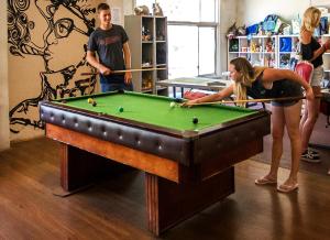 a man and a woman playing a game of pool at The Hive Hostel in Perth