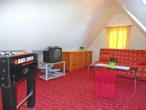 - un salon avec une télévision et un canapé dans l'établissement Ferienwohnung im Dachgeschoss _ He, à Neuhermsdorf