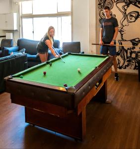 a man and a woman playing a game of pool at The Hive Hostel - Traveler Friendly, Passport Only in Perth