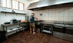 un hombre de pie en una cocina preparando comida en The Hive Hostel - Traveler Friendly, Passport Only en Perth