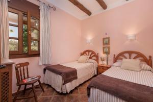 a bedroom with two beds and a chair at Hacienda Los Olivos in Ronda